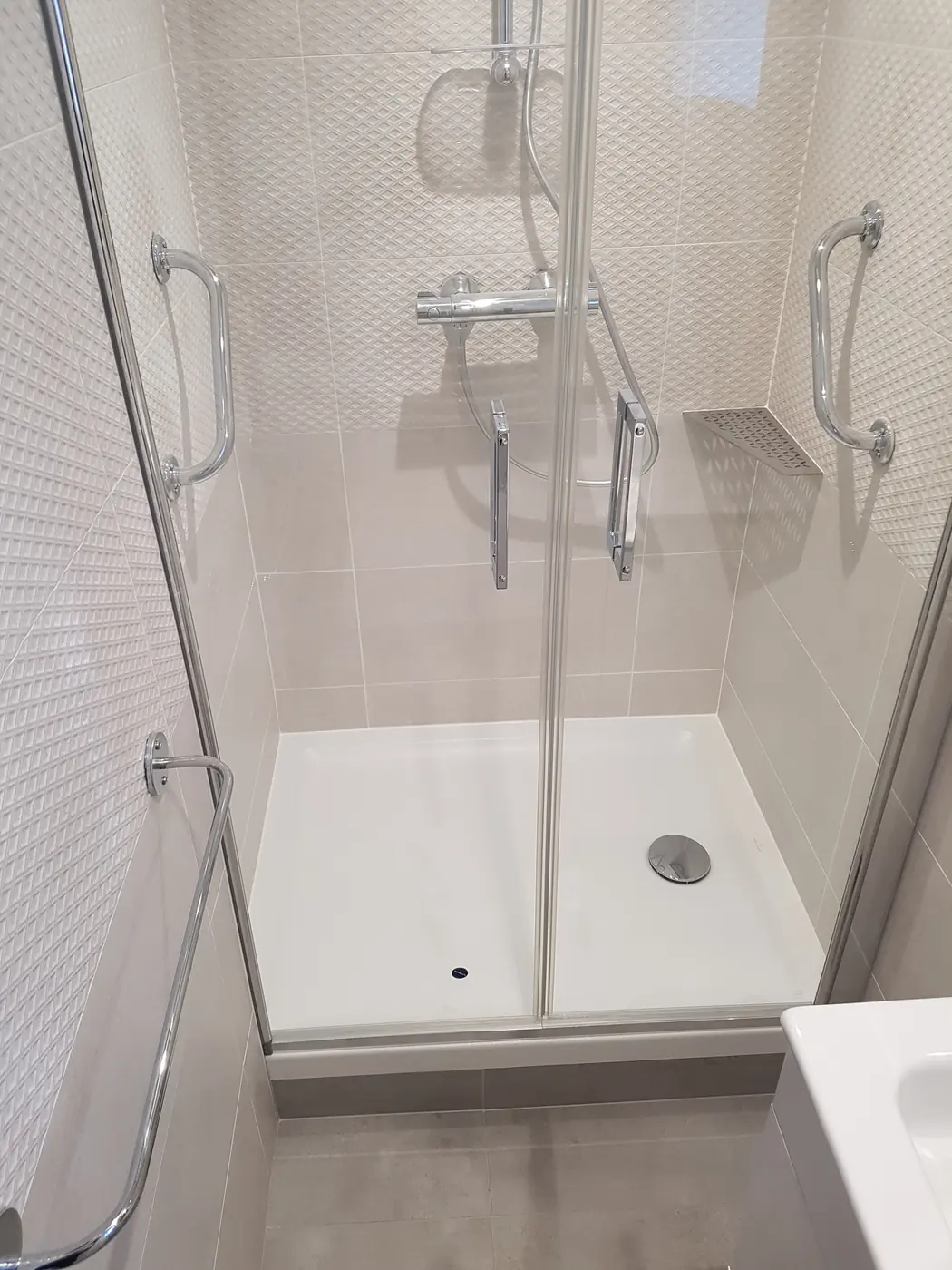 Douche rénovée avec paroi vitrée et receveur blanc
