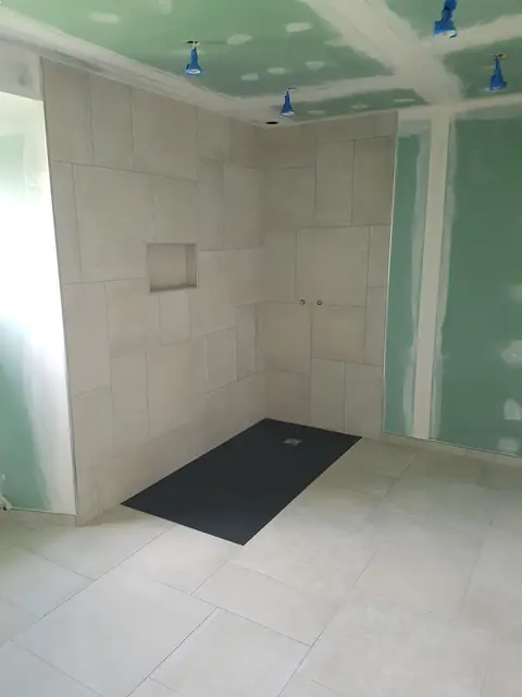 Douche à l’italienne avec receveur noir et murs carrelés clairs