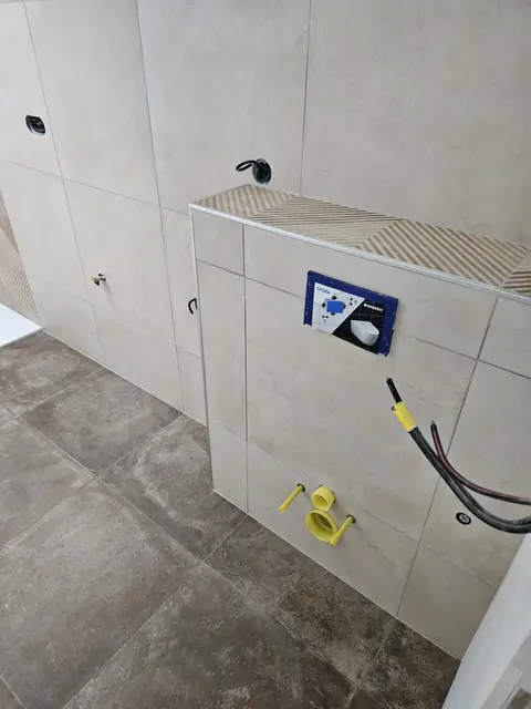 Salle de bain en grands carreaux gris avec bâti de WC suspendu