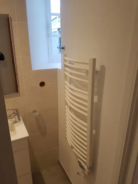 Salle d’eau carrelée avec sèche-serviettes